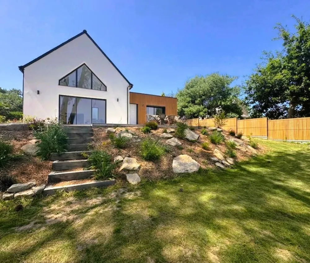 maison moderne avec terrasse et jardin en contrebas