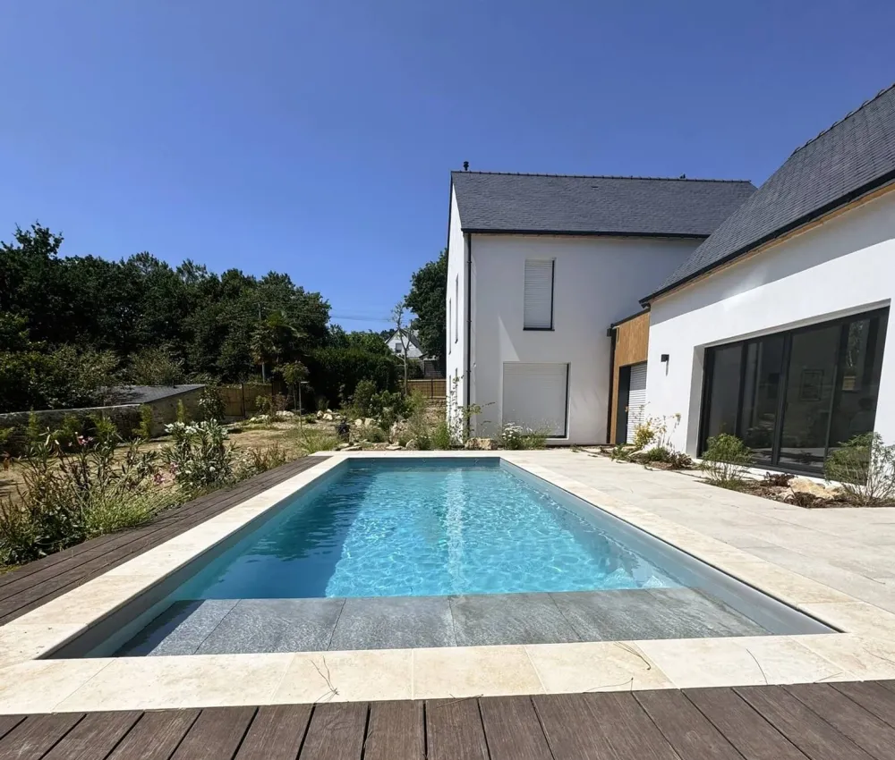 piscine rectangulaire avec terrasse en bois et maison blanche