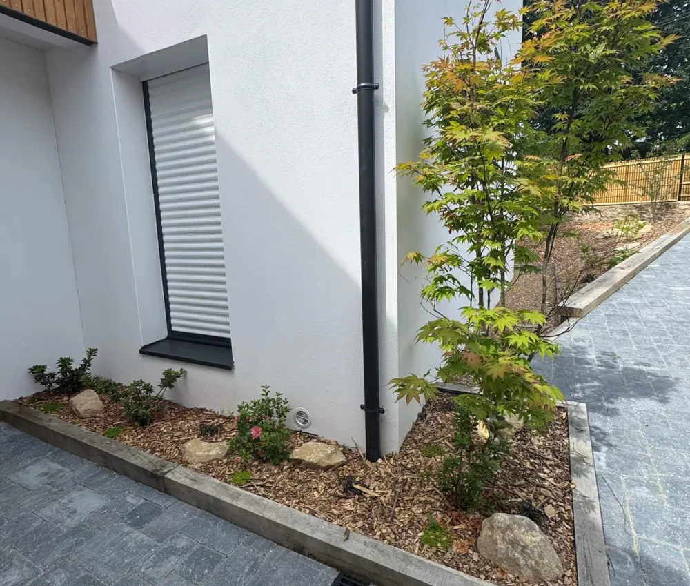 Vue extérieure d'un bâtiment avec un jardin paysager en bord de trottoir