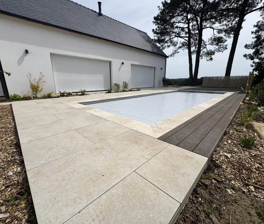 piscine avec couverture, pavés et terrasse en bois devant une maison moderne