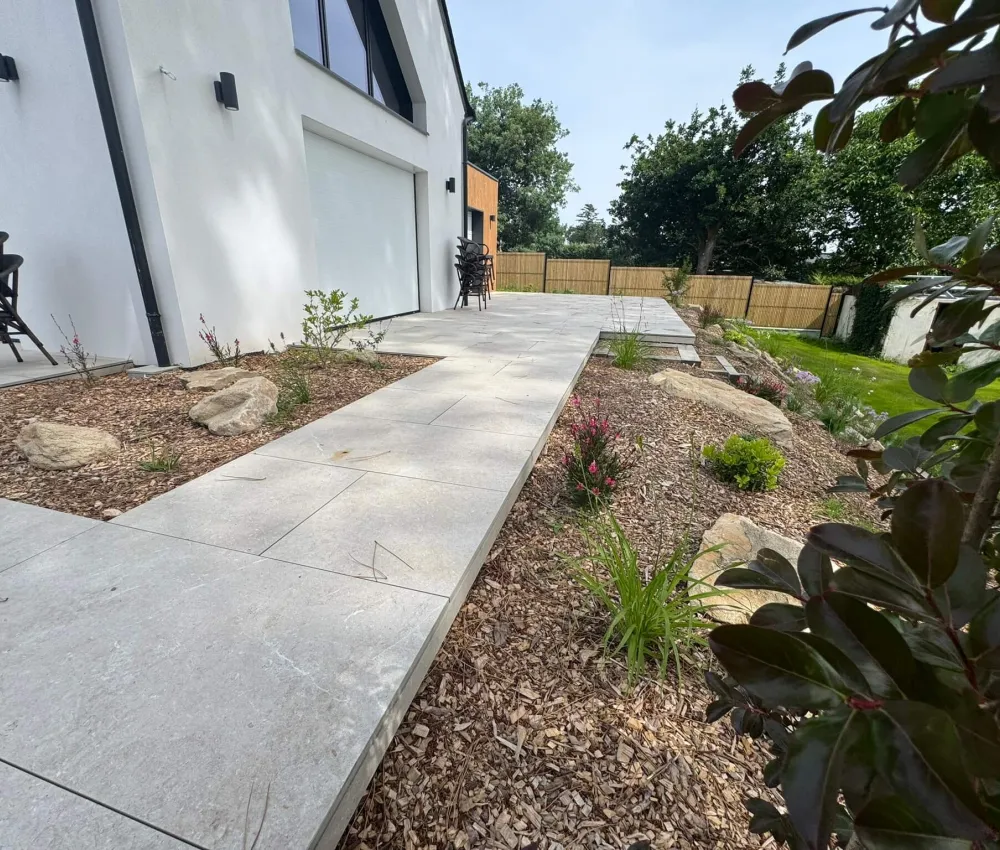 pavé de dalles en béton gris avec un chemin de pierre et une pelouse à côté d'une maison moderne