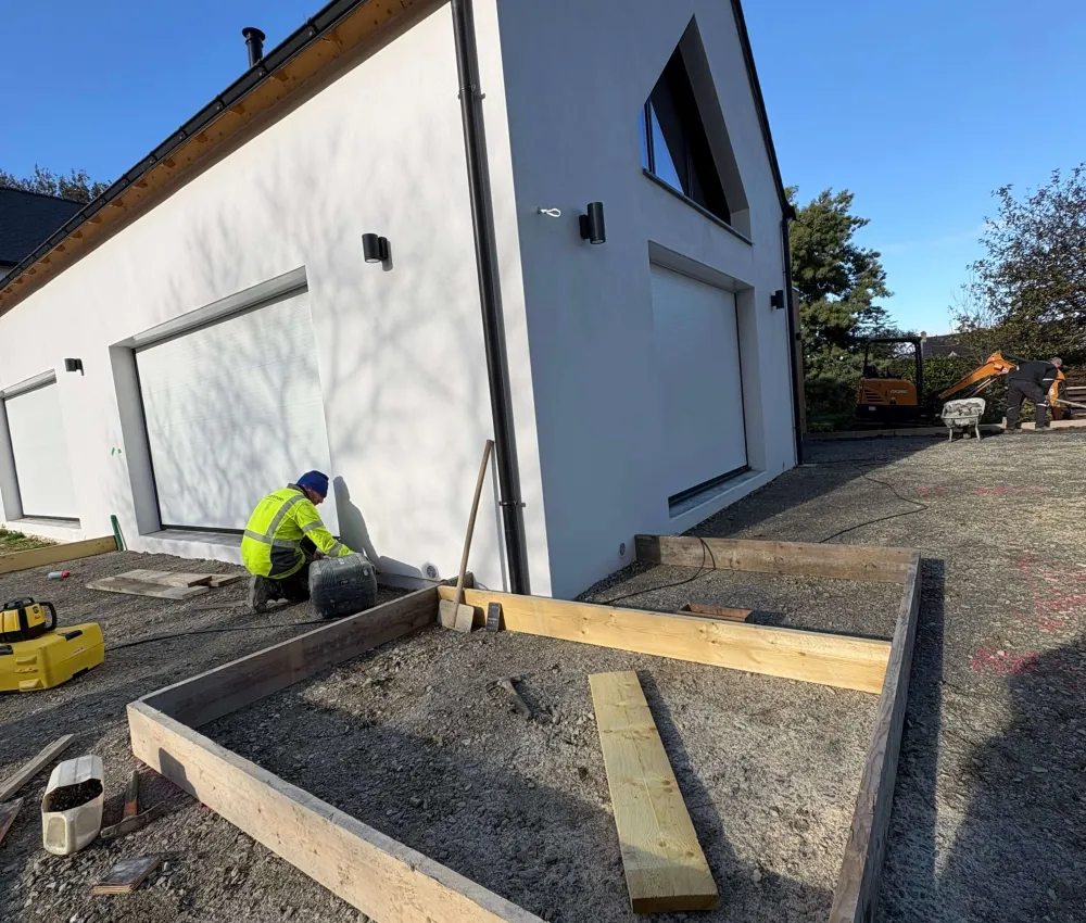 un bâtiment en construction avec des éléments de structure en bois et un ouvrier travaillant à l'extérieur